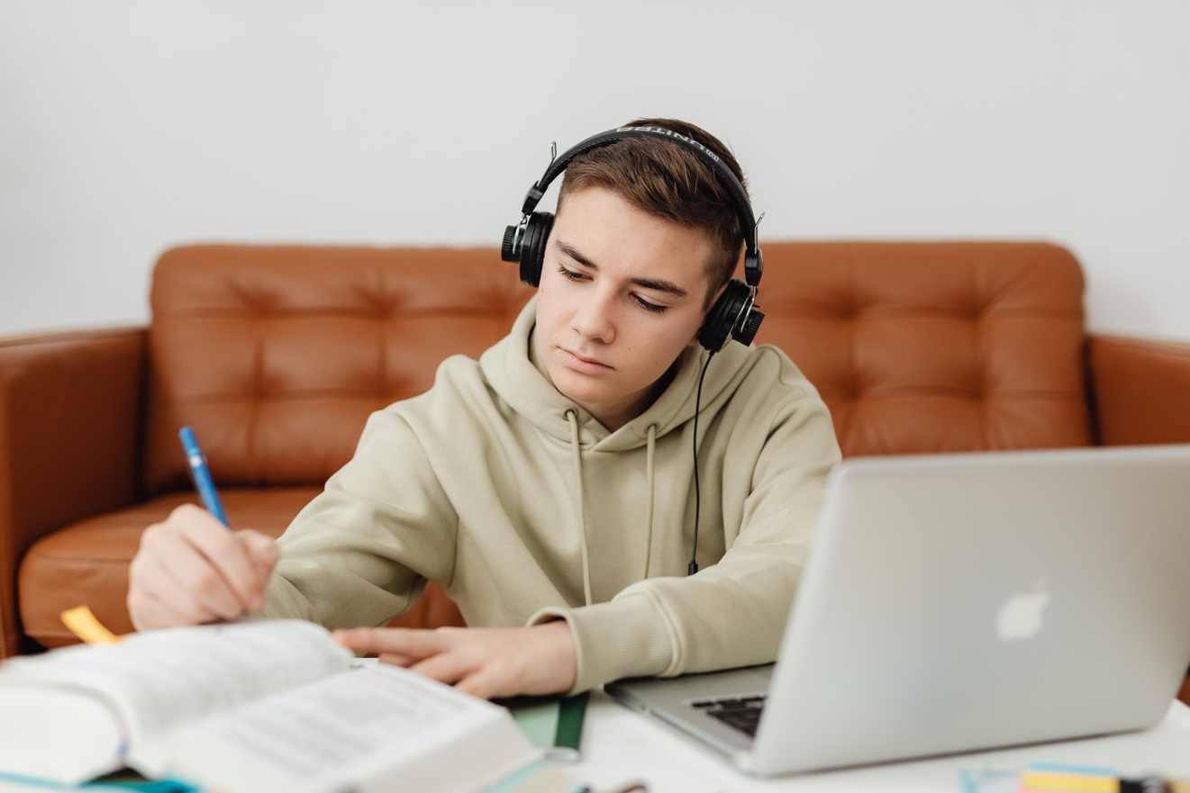 Photo of a Boy Doing His Homework while Listening to Music